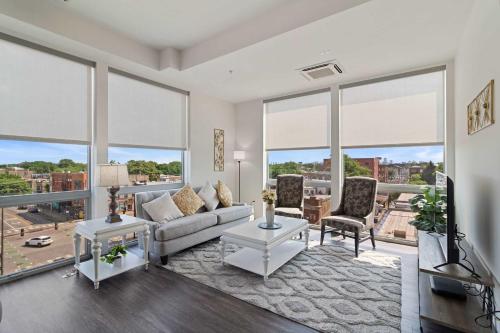 a living room with a couch and chairs and large windows at 2BR City Loft Sweeping Glass Views in Chicago
