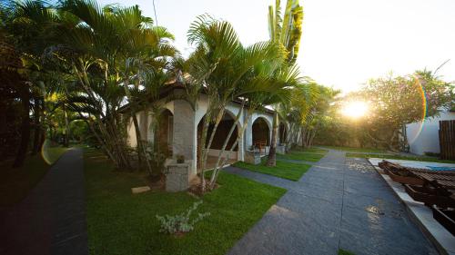 a building with palm trees next to a sidewalk at Bosque Cumbuco Pousada in Cumbuco