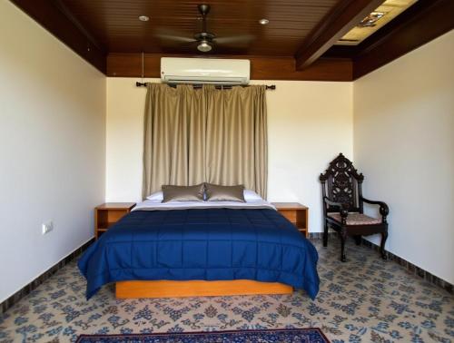 a bedroom with a blue bed and a chair at Vishwa Elysium in Mannar