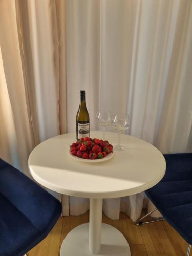 a white table with a bottle of wine and a plate of fruit at ORBI CITY amazing holiday in Batumi