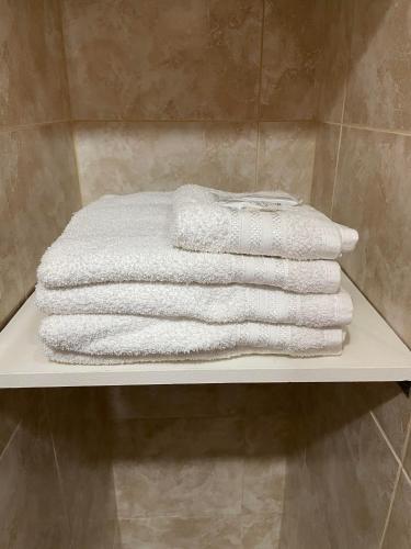 una pila de toallas sentadas en un estante en un baño en Refugio Kooch, en Río Gallegos
