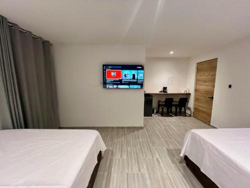 a hotel room with two beds and a tv on the wall at Estadero Bello Horizonte in Florencia