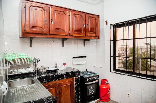 a kitchen with wooden cabinets and a stove and a window at SCI Résidence A in Kika