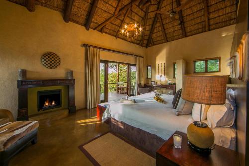 ein Schlafzimmer mit einem großen Bett und einem Kamin in der Unterkunft 57 Waterberg in Welgevonden Game Reserve