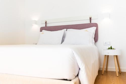 a bedroom with a white bed with white pillows at Casas do Freixial - Casa do Beco in Fundão
