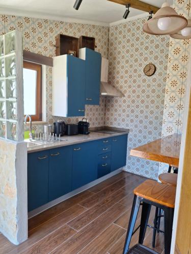 a kitchen with blue cabinets and a wooden floor at Casal das Nogueiras, casas rurais de charme agradáveis e acolhedoras in Arrimal