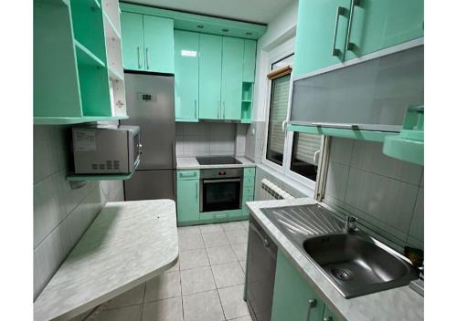 a kitchen with green cabinets and a sink at Apartments Sat in Belgrade