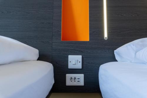 a bedroom with two beds and an orange and black wall at easyHotel Zürich City Limmatplatz in Zürich