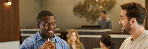 twee mannen lachend terwijl ze een glas wijn vasthouden bij Courtyard by Marriott Madison in Madison