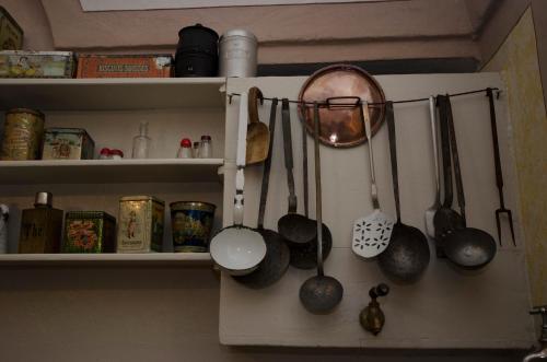 a kitchen shelf with utensils hanging from it at Palazzo Gamboni Swiss Historic Hotel in Comologno