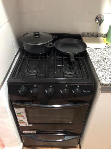 a stove with two pans on top of it in a kitchen at Apart Milo II in San Fernando del Valle de Catamarca