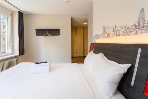 a bedroom with a white bed with a black headboard at easyHotel Zürich City Main Station in Zürich