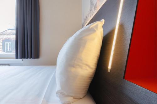 a white pillow sitting on a bed next to a window at easyHotel Zürich City Main Station in Zürich