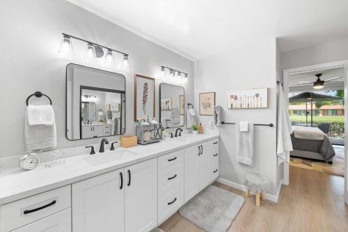 a white bathroom with two sinks and two mirrors at Designer Seville Condo w Golf Mountain Views in Rancho Mirage