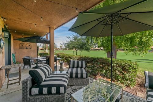 a patio with chairs and an umbrella and a table at Designer Seville Condo w Golf Mountain Views in Rancho Mirage