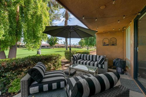 a patio with two couches and an umbrella at Designer Seville Condo w Golf Mountain Views in Rancho Mirage