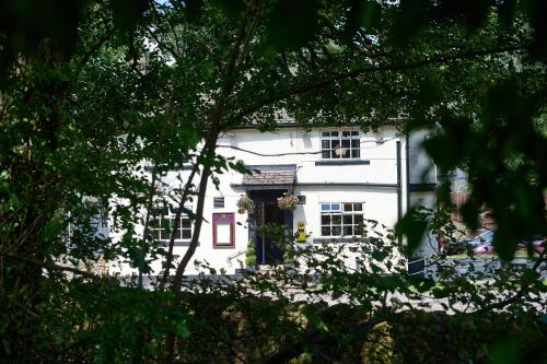 a white house with a blue door and trees at Bulls Head - Holymoorside in Chesterfield