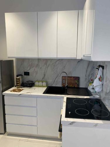 una cucina con mobili bianchi e piano cottura con forno di Villa Dior a Sarandë