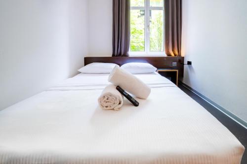 a white bed with two pillows and a remote control on it at easyHotel Zürich City Centre in Zürich