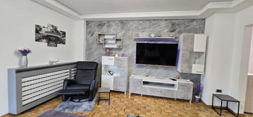 a living room with a chair and a desk and a television at Lux Apartman Stojanović in Belgrade