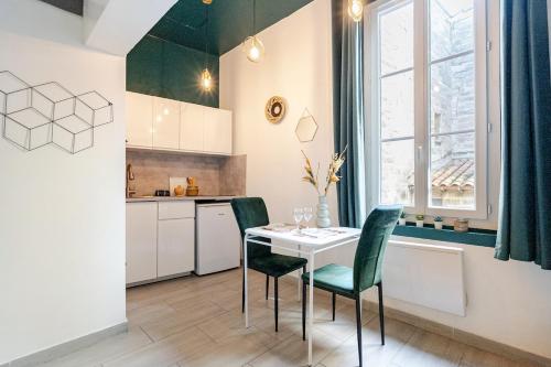 une cuisine avec une table blanche et des chaises vertes dans l'établissement Studio cosy intra-muros, à Avignon