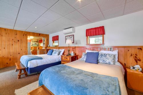 two beds in a room with wooden walls at The Nest Waterfront Lake Ostego Studio in Cooperstown