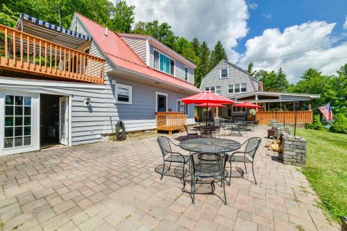 a patio with tables and chairs and a house at The Nest Waterfront Lake Ostego Studio in Cooperstown
