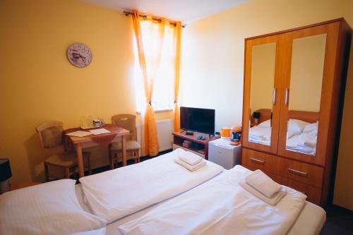 a bedroom with a bed and a table and a television at Penzion Vyhlídka Janovičky in Broumov