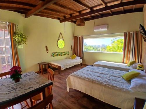 a bedroom with two beds and a table and a window at Solar del Mar in Praia do Rosa