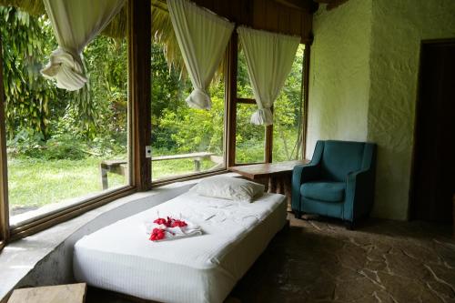 a bedroom with a bed and a blue chair and a window at Eco Hotel Sak Nok in Lacanjá