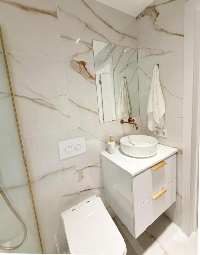 a white bathroom with a sink and a mirror at Luksusowy Apartament z basenem i jacuzzi in Málaga