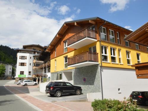 a yellow and white building with cars parked in a parking lot at Emma Top 1 in Dienten am Hochkönig