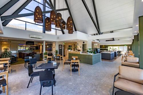a lobby with tables and chairs and a restaurant at Auckland Rose Park Hotel in Auckland
