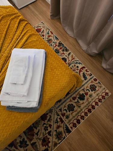 a bed with a yellow sheets and towels on a rug at A Casa do Comandante in Lagoa