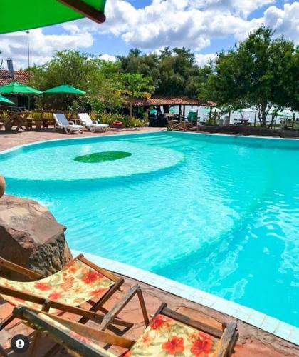 a large swimming pool with chairs and umbrellas in front of it at Pousada Flor de Lins in Piranhas