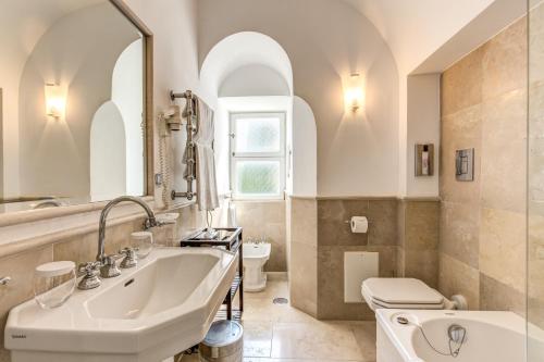 a bathroom with a sink and a toilet and a mirror at Villa Calypso in Capri