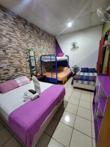 a room with three beds and a brick wall at Hostal Leyendas in León