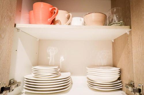 a stack of plates and bowls on a shelf at HOM I SKI OUT 4PAX Edif Licancabur Valle Nevado 206A in Lo Barnechea
