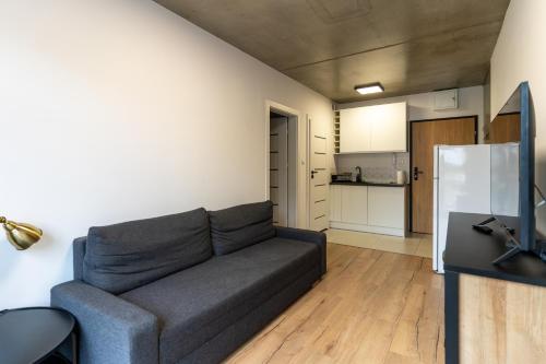 a living room with a couch and a kitchen at Apartamenty Przystanek Morska in Gdynia