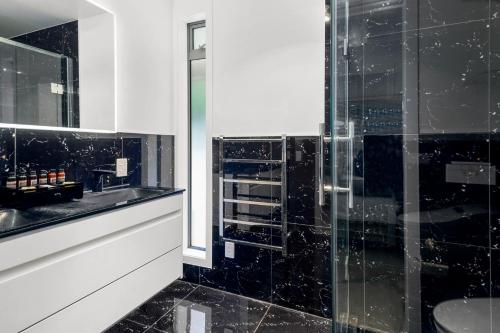 a black and white bathroom with a glass shower at Rotorua Luxury lakeside Resort in Rotorua