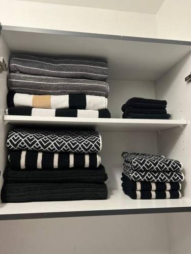 a closet filled with black and white towels at Le St-Augustin - à 15 minutes des Outlets de Mirabel in Mirabel