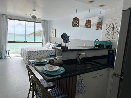 a kitchen with a sink and a living room with a bed at Arraial do cabo loft prainha in Arraial do Cabo