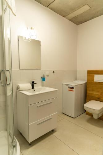a white bathroom with a sink and a toilet at Apartamenty Przystanek Morska in Gdynia