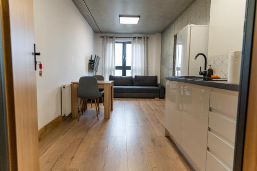 a kitchen and living room with a table and a couch at Apartamenty Przystanek Morska in Gdynia