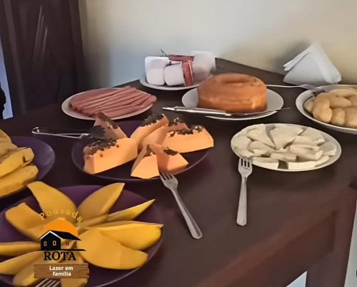 a table with plates of food and forks and desserts at Pousada Rota in Paty do Alferes
