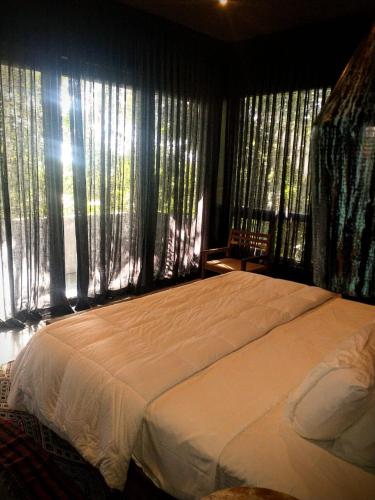 a bedroom with a large white bed with windows at Casa Vive Bacalar in Bacalar