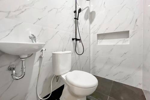 a white bathroom with a toilet and a sink at Urbanview Olive Near Graha Saba Buana Surakarta in Bonorejo