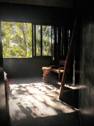a room with a window and a bench and trees at Casa Vive Bacalar in Bacalar