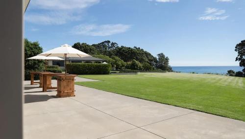a picnic table with an umbrella on a lawn at Bay View Terrace Studio 3 in Tataraimaka
