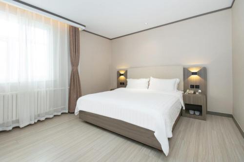 a bedroom with a large white bed and a window at 汉庭固安北京大兴国际机场酒店 in Dongsunguo